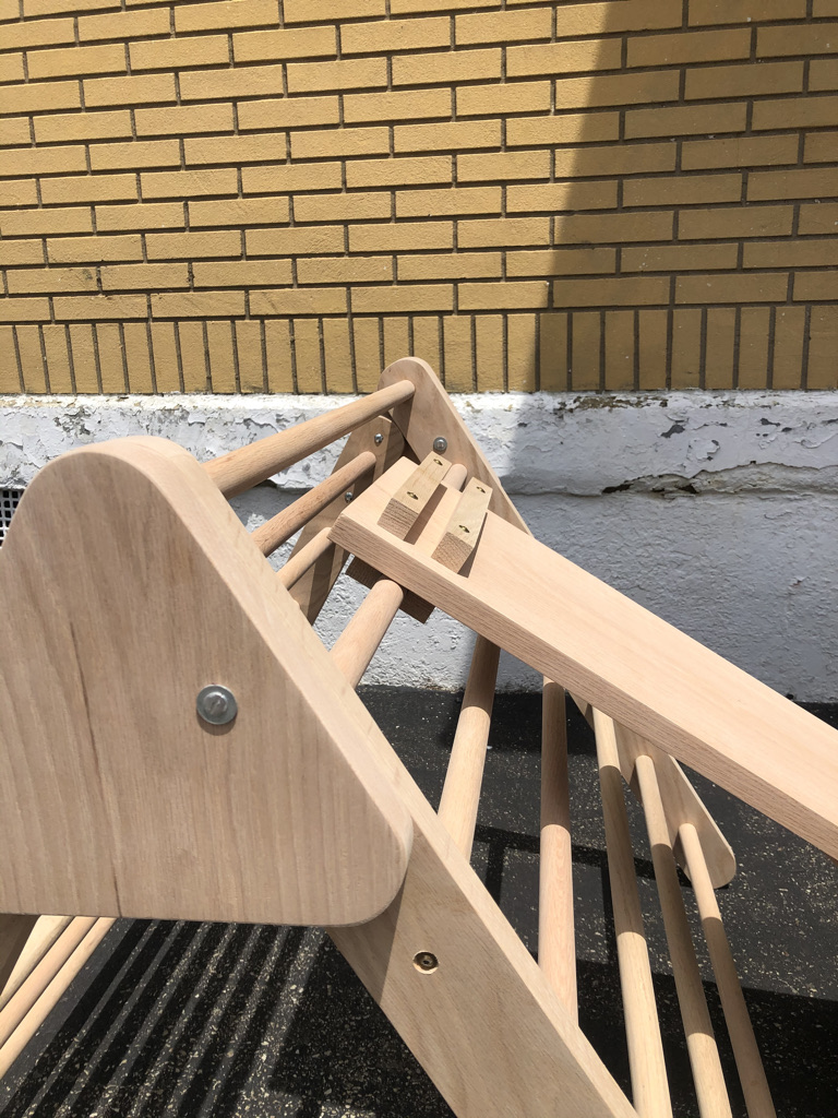 pikler triangle components. close up of top of climbing apparatus showing attached slide component. 