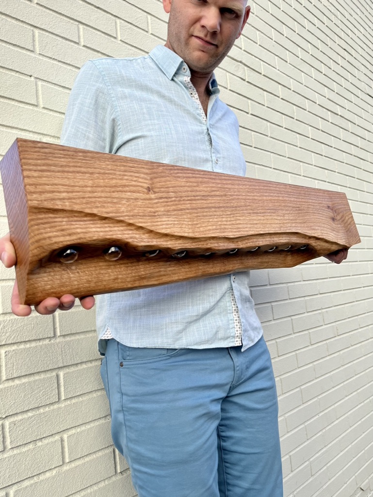 Pin Oak propagation station. Curved undulated front revealing test tubes from below. Person, Caleb Sisco, seen holding the station in front of a brick wall.