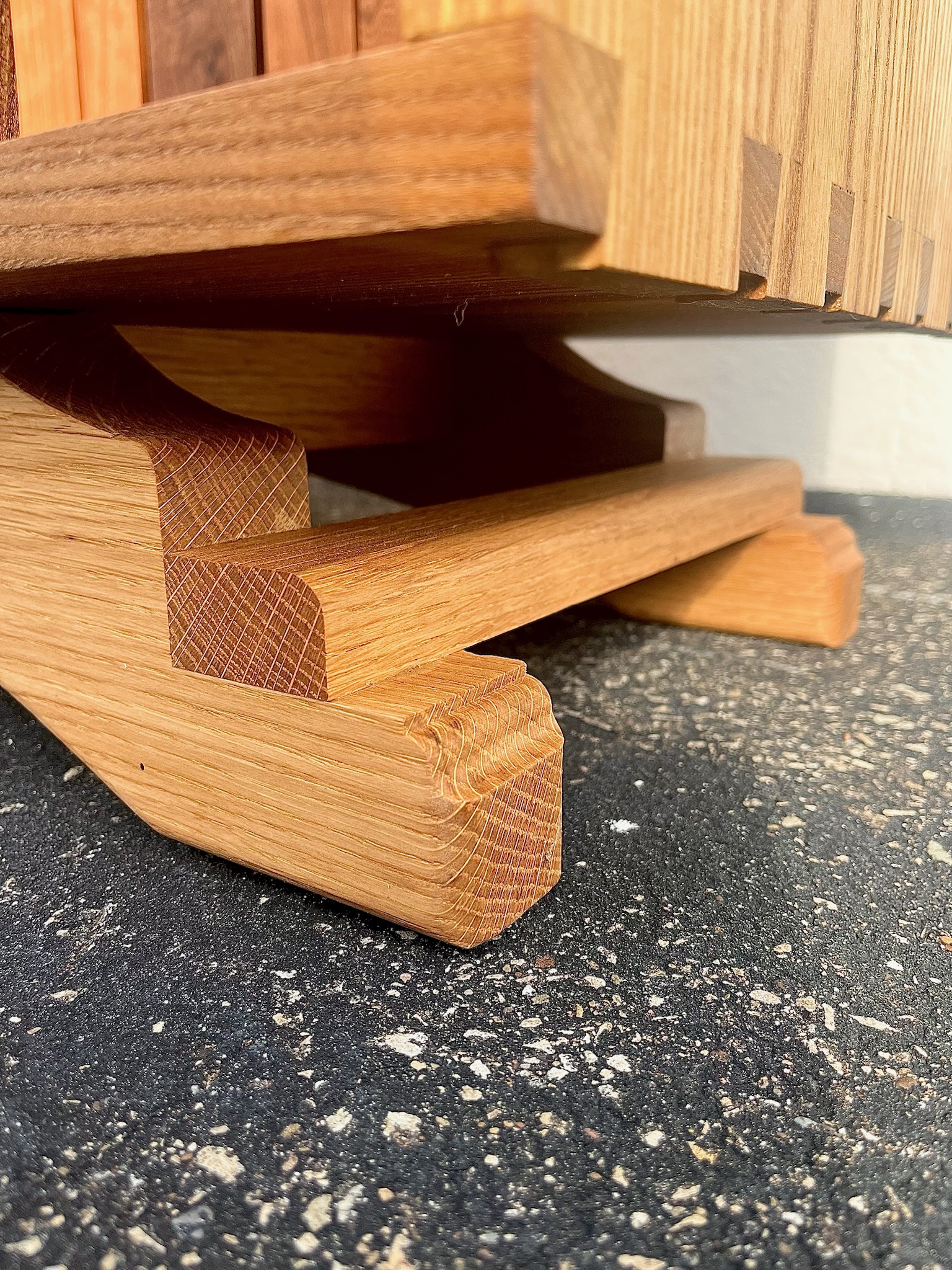 Cabinet base made from white oak, showcasing endgrain cascading down the feet and hand-cut dovetails trailing off from the center of the image. Close-up. 