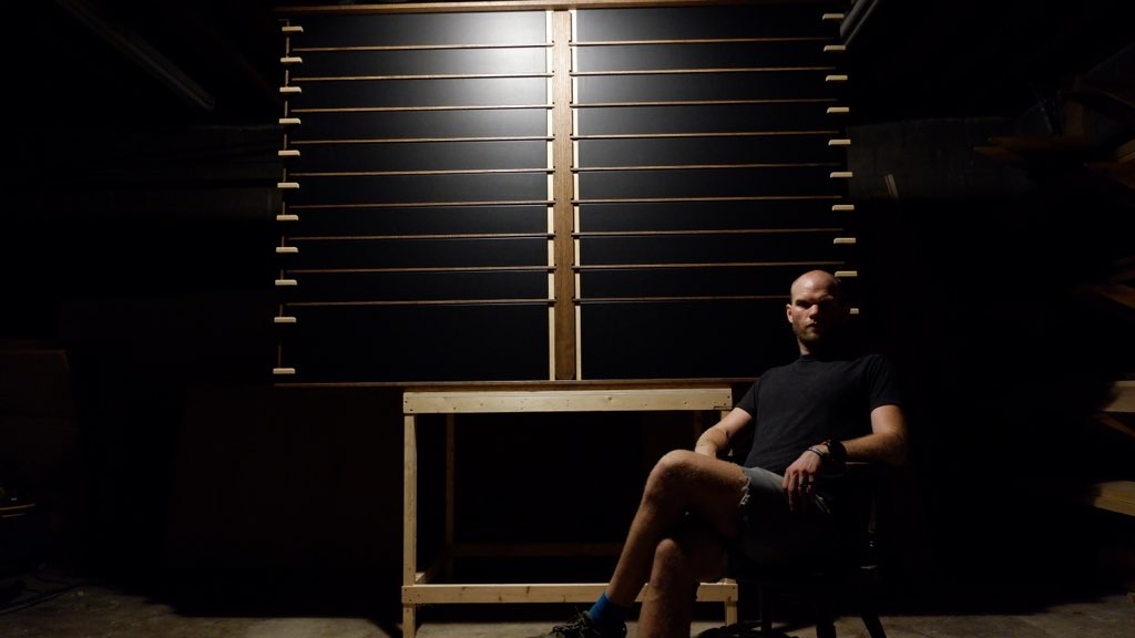 Brewery Taplist. Contains maple sliding dovetails, maple boards stained black for menu selection. Red oak frame center and exterior case. Person, Caleb Sisco, sitting in front of taplist.