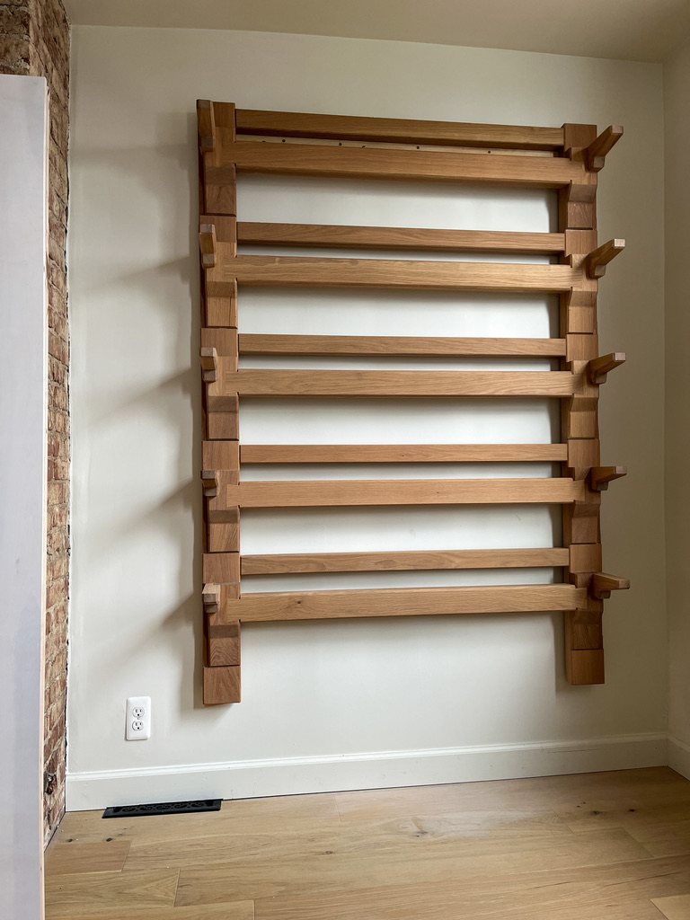 Shelving structure hung on white wall. Shelving made from white oak using traditional Japanese joinery. Panned out image. 