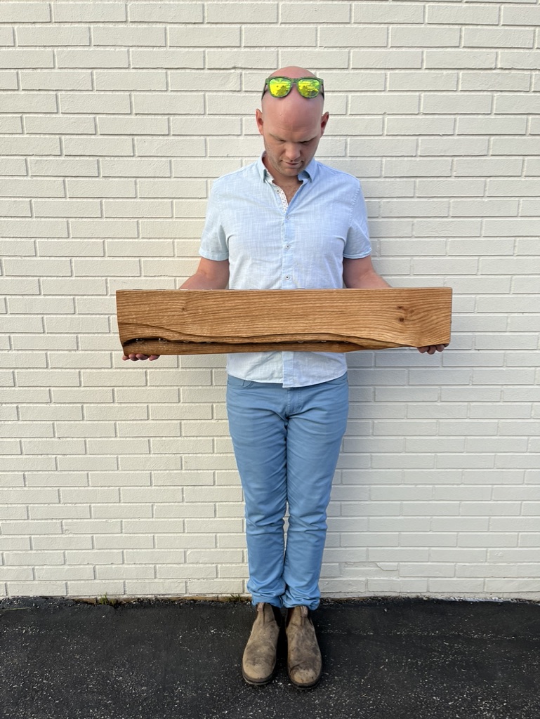 Pin Oak propagation station. Curved undulated front revealing test tubes from below. Person, Caleb Sisco, seen holding the station in front of a brick wall.