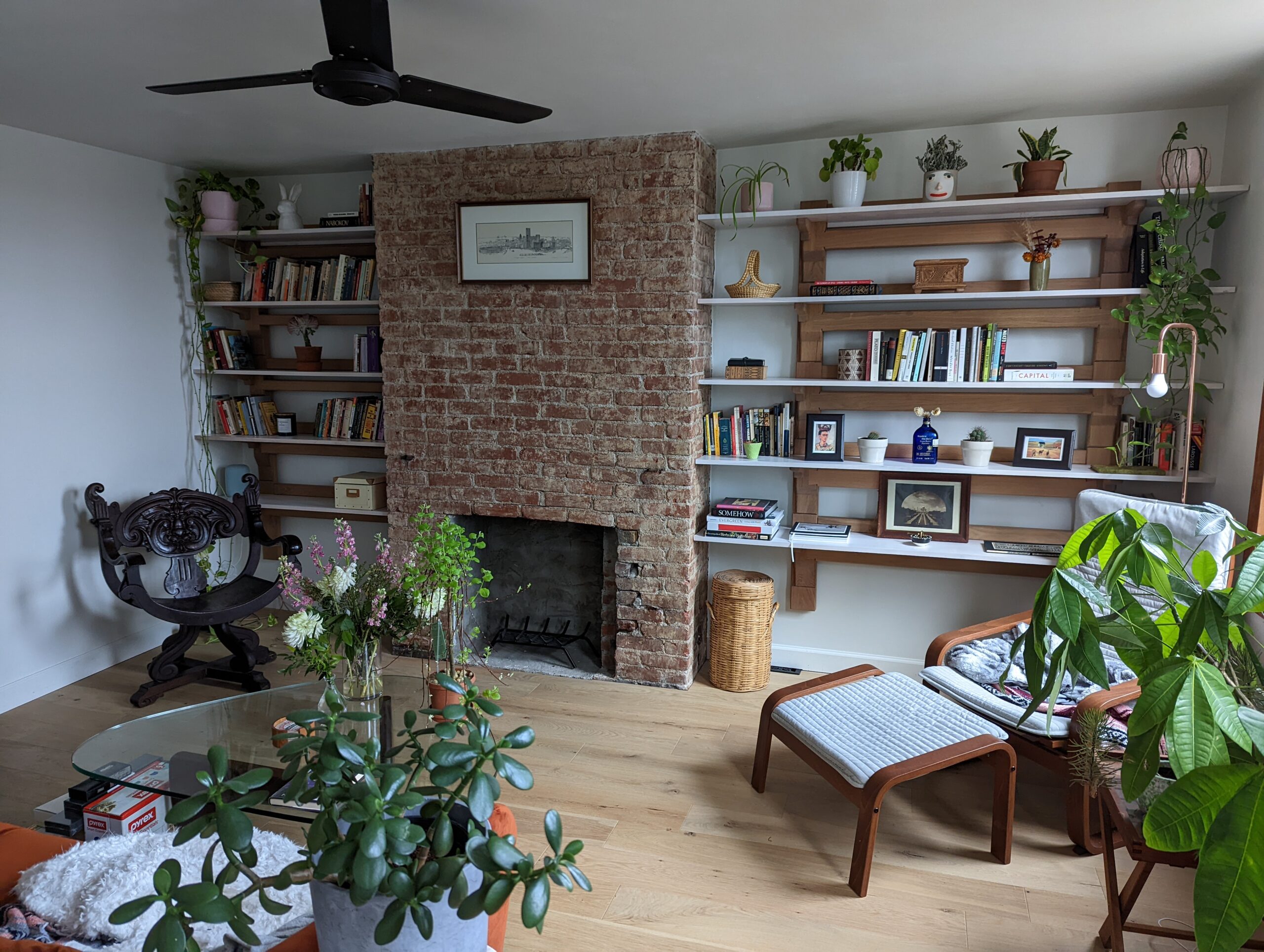 Unique shelving on two walls featuring personal effects of homeowners. Panned out image showing two wall shelving units encompassing a fireplace in the center.