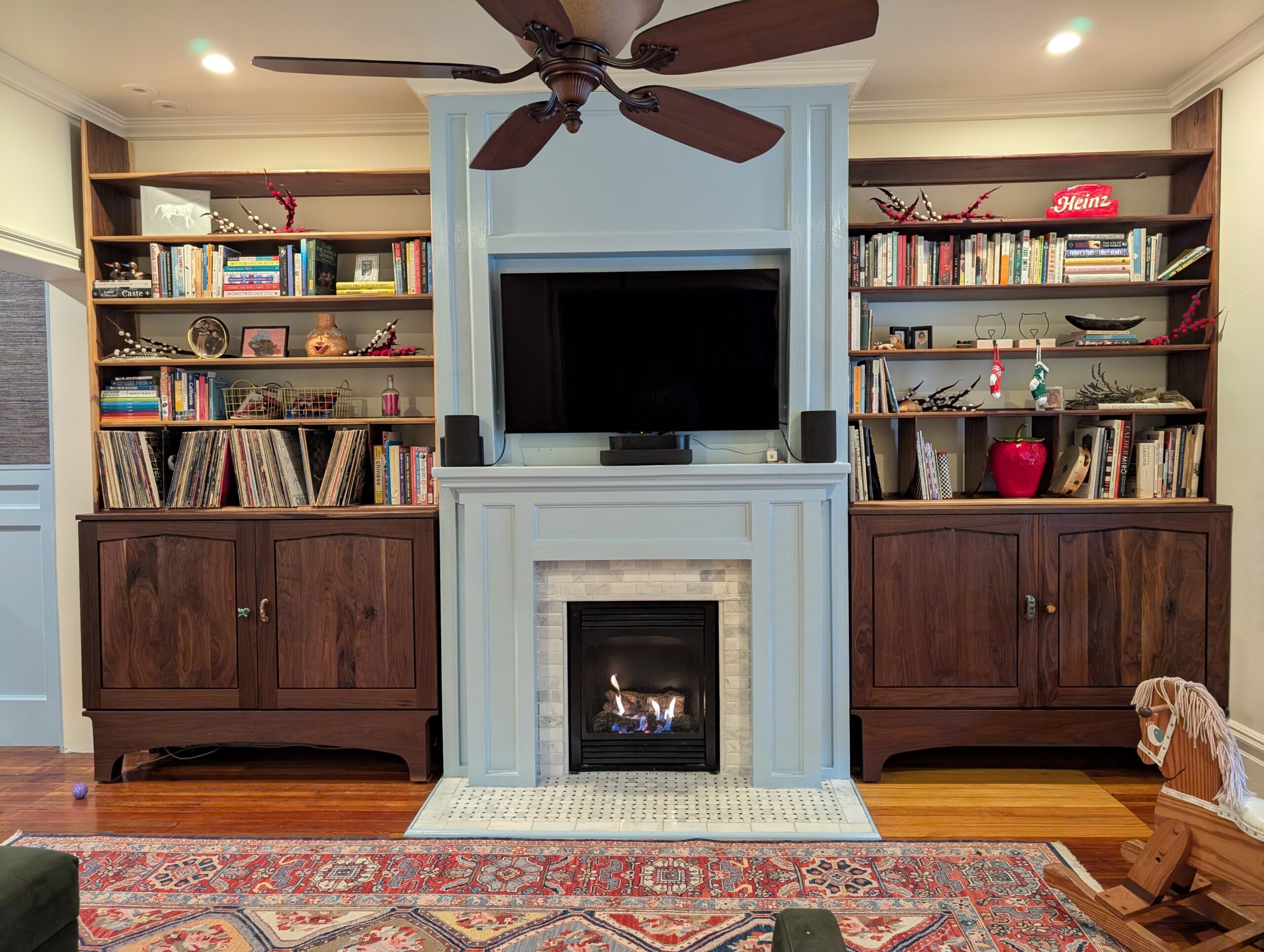 two wooden bookcases filling two niches between a fireplace in a client's home.