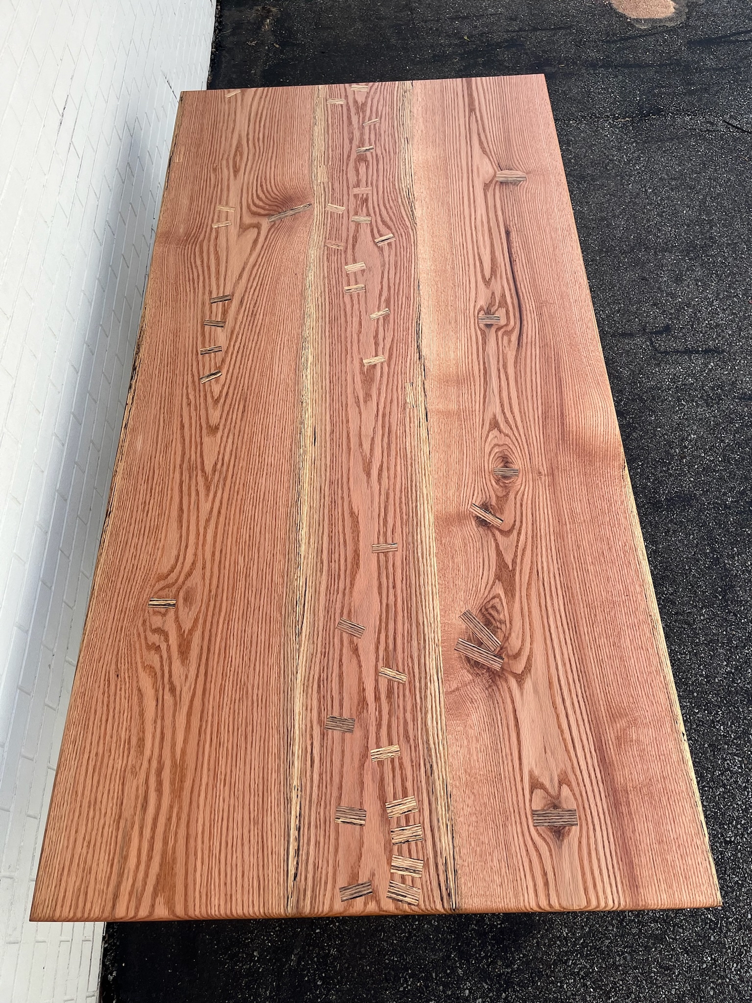 Overhead vantage of a Red Oak custom tabletop. Pink in color with three distinct sections from three sister slabs. Naturally spalted, also referred to as marbled, inlays.